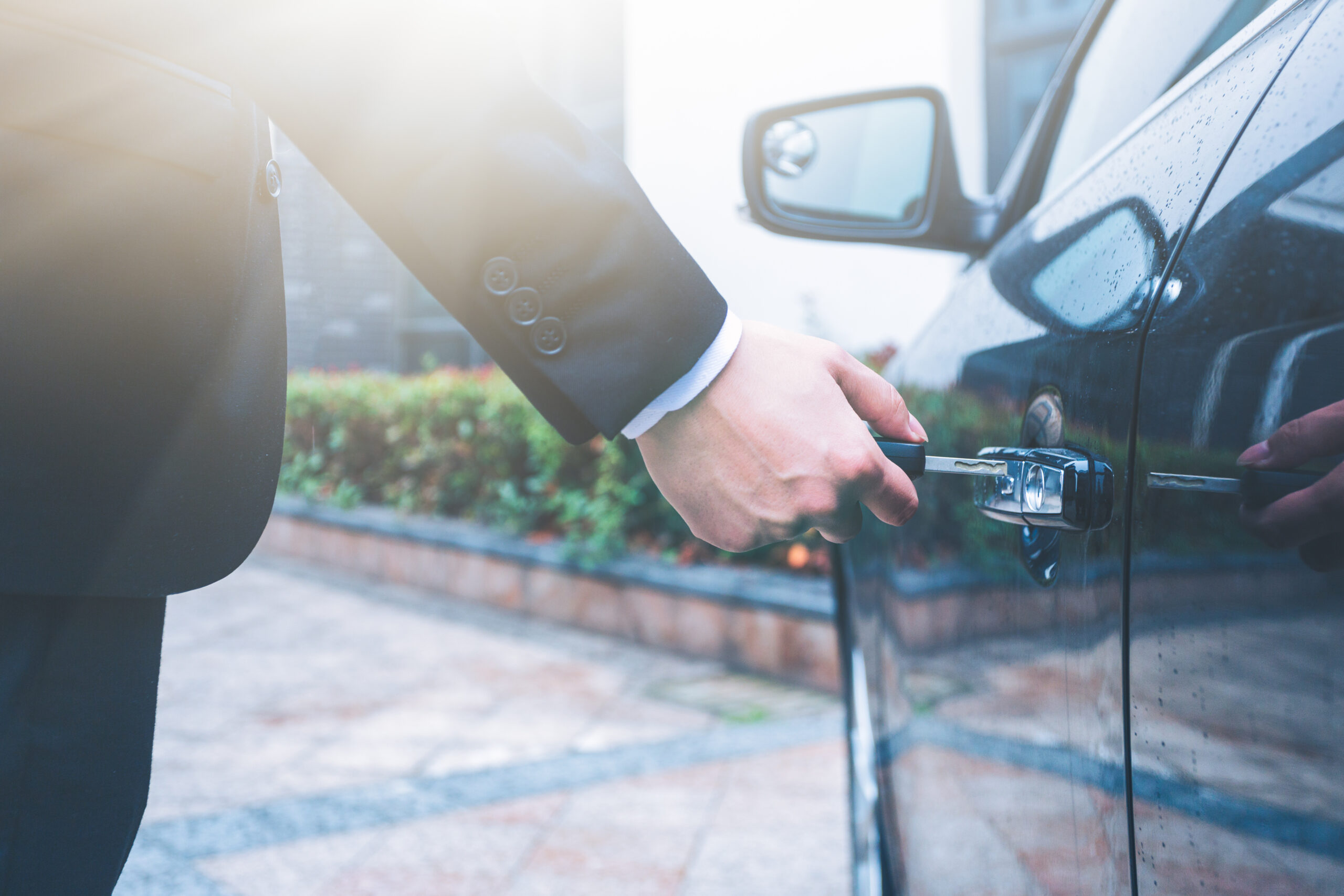 Hand of businessman opening door of car with key
